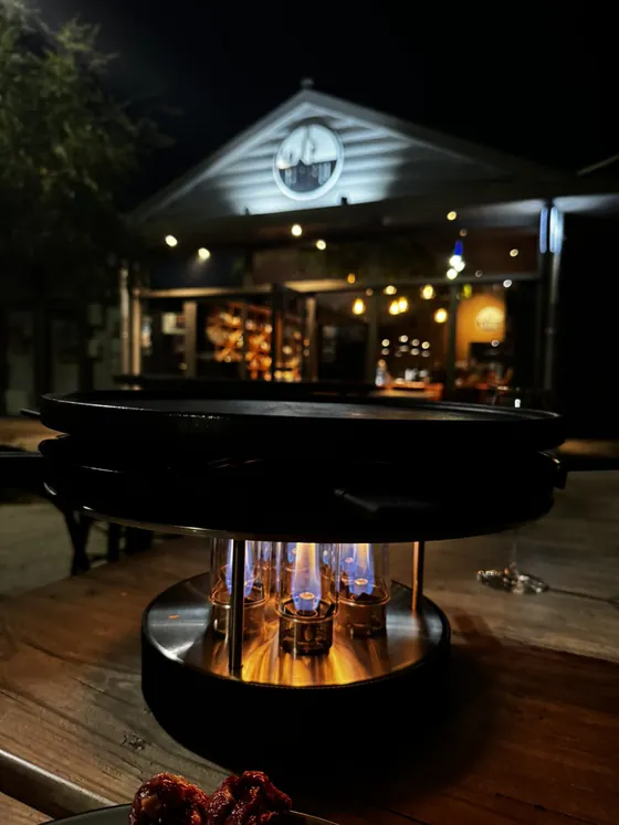 Grill de table allumé en terrasse le soir devant la façade du Nabu